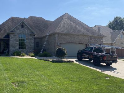 Suburban brick house with a green lawn and a black pickup truck parked in the driveway