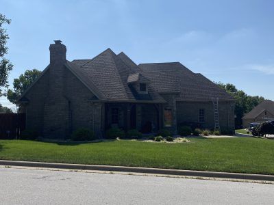 Single-story brick house with a large green lawn under a clear blue sky