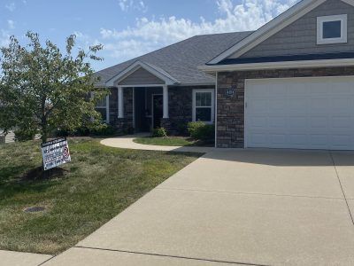 Suburban house with a driveway, garage, front lawn, and a sign in the yard.
