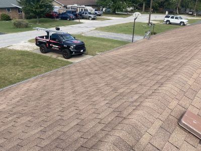 Roof shingles overlooking a suburban street with a black pickup truck and other parked cars below