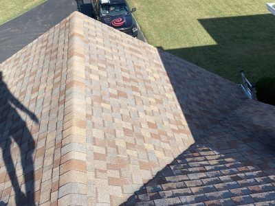 Roof shingles on a house in sunlight, with a dark shadow across one section.