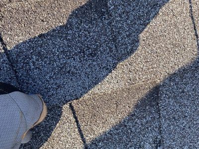 Shadow of a person on a textured pavement near a shoe tip and a drain cover
