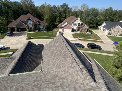 Rooftop view of a suburban neighborhood with houses, parked cars, and tree-lined streets