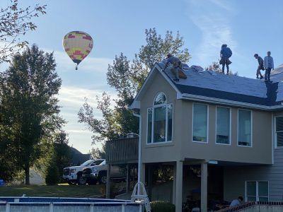 Hot air balloon over a suburban house as workers stand on the roof during repairs