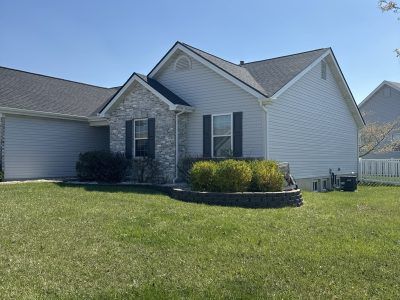 Single-story suburban house with stone and white siding, a front lawn, and a blue sky.