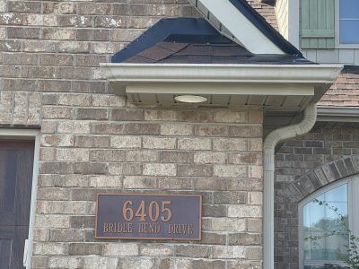 House exterior with brown brick wall and a plaque reading “6405 BUILDER BEAV TRIAL.”