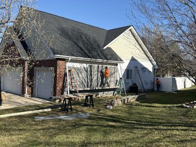 Suburban house exterior with a large deck under construction and a child on the porch.