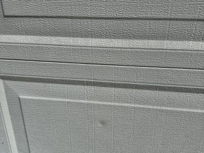 Close-up of gray painted siding with horizontal boards and a textured lower panel