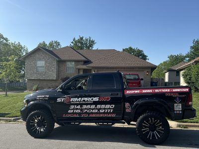 Black pickup truck with company decals parked on a residential street in front of a house