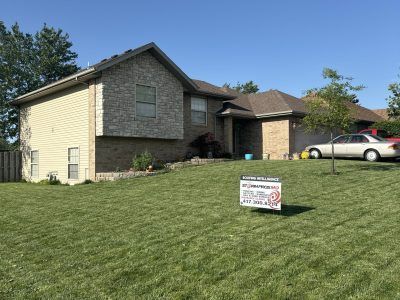 Suburban house with lawn and a real estate sign in the front yard