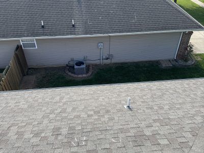 Backyard view with a house wall, rooftop shingles, AC unit, and wooden fence