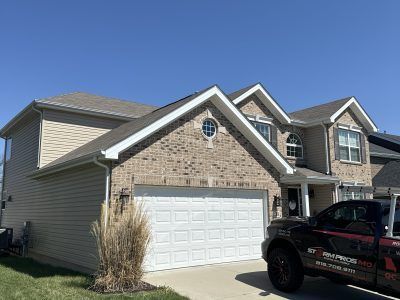 Suburban two-story house with brick facade, white garage, and a black pickup truck in the driveway