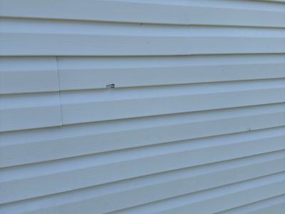 White vinyl house siding with a small damaged or protruding spot near the center