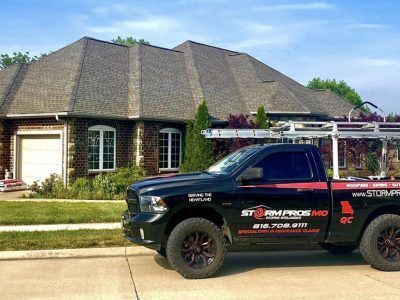 Black pickup truck with company decals parked in front of a suburban brick house