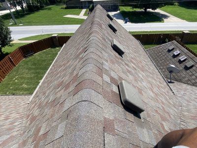 Steep shingled roof with skylights beside a suburban street and lawn