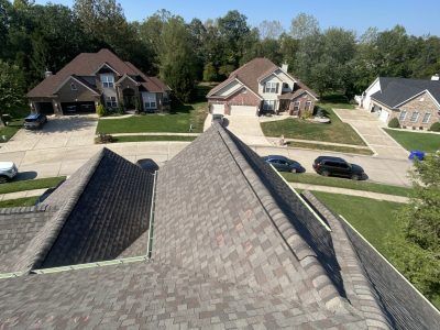 Rooftop view of a suburban neighborhood with several houses, driveways, and parked cars