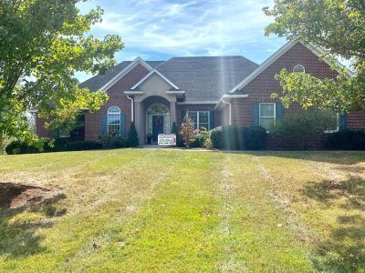 Brick suburban house with arched entry and a front lawn under bright daylight