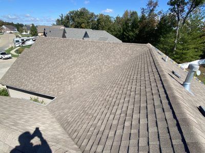 Rooftop with gray shingles and skylights under a clear blue sky, viewed from above