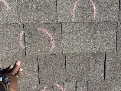 Hand and wristwatch pointing at pink spray-painted markings on gray pavement stones