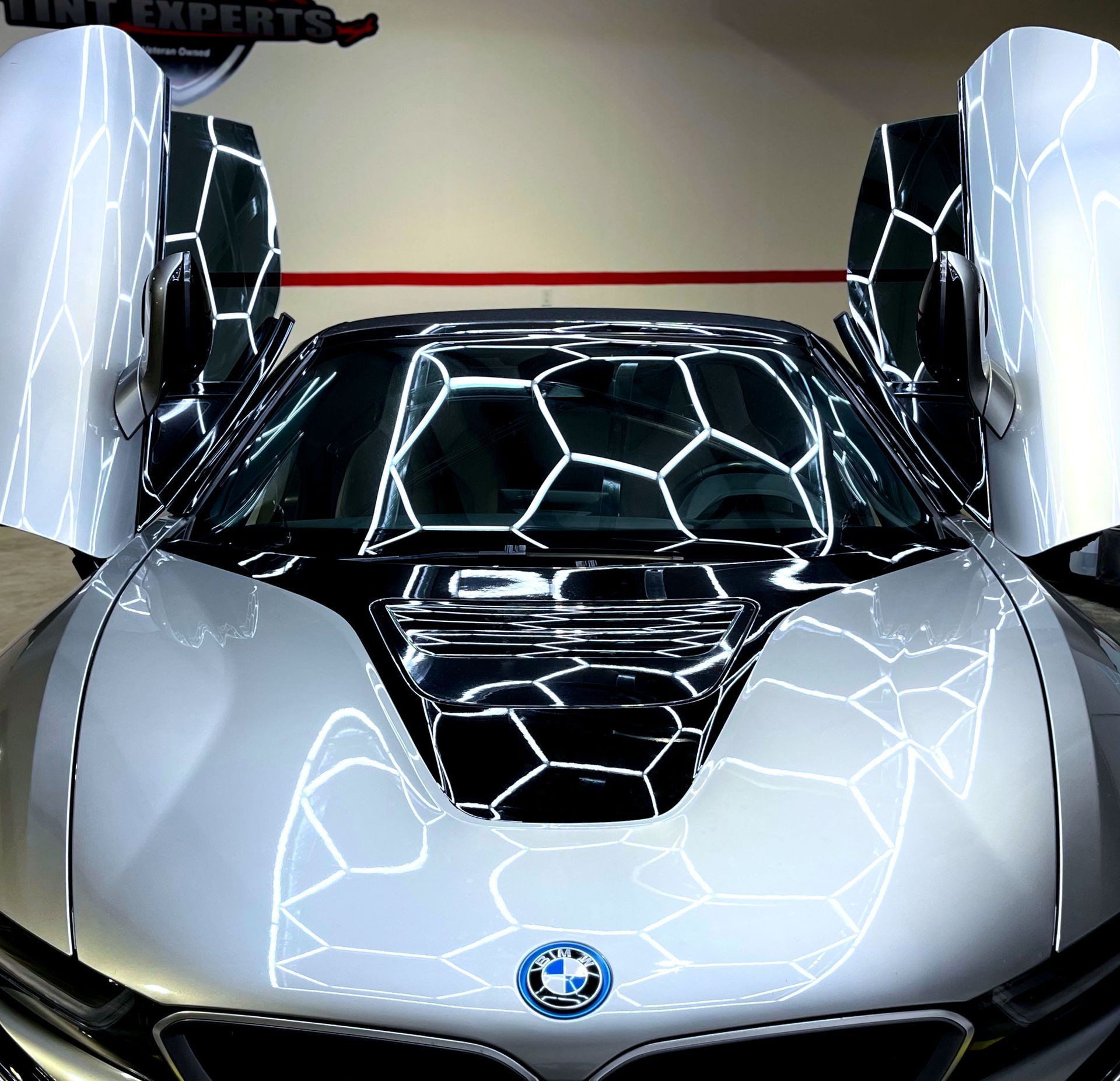 A silver sports car with the doors open and a bmw logo on the hood