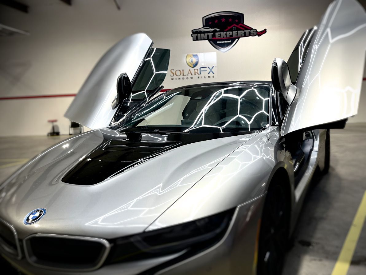 A silver bmw is parked in a garage with its doors open