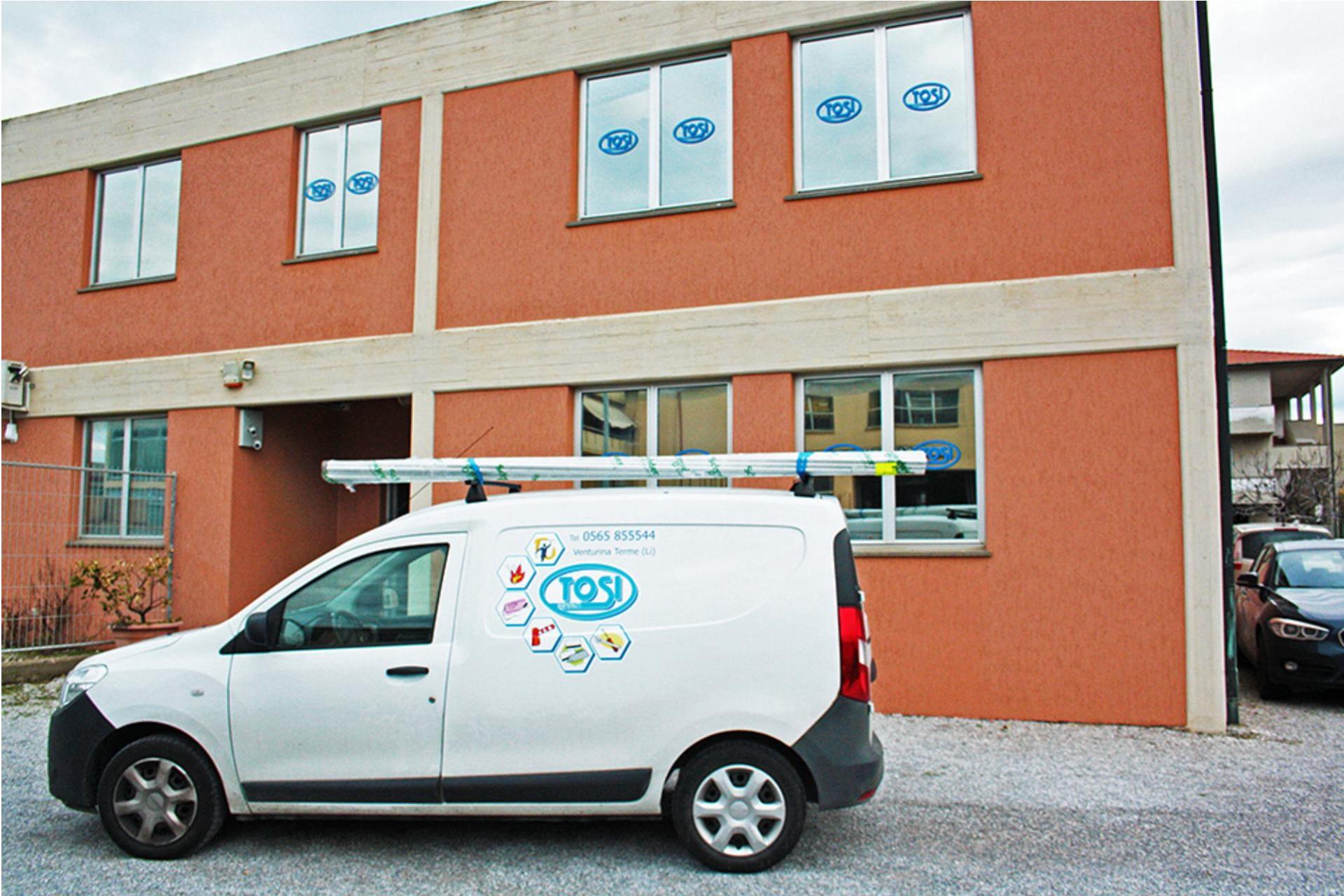 Un furgone di servizio bianco parcheggiato davanti a un edificio arancione a due piani con diverse finestre.