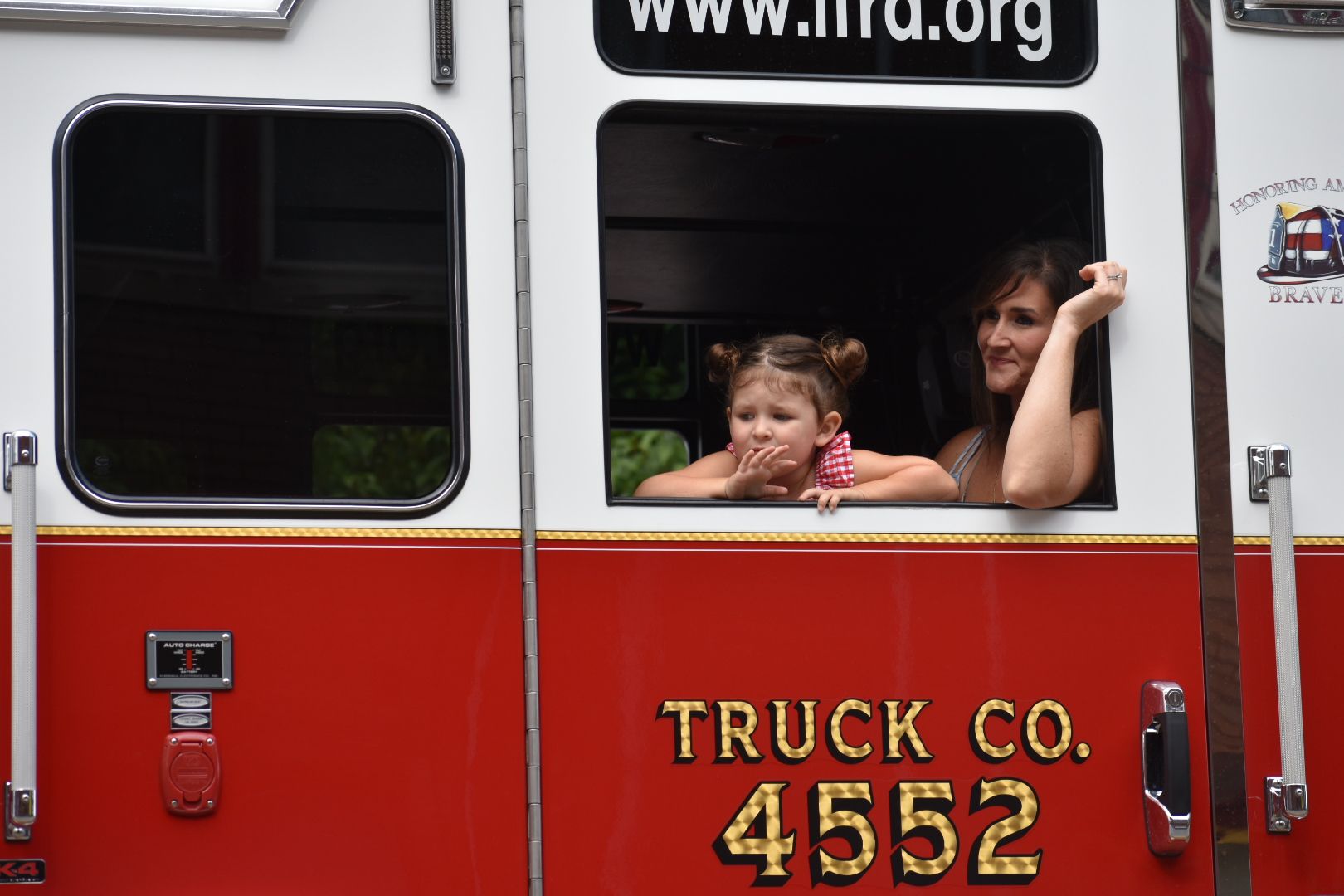 Two children looking out from a red fire truck window, labeled 