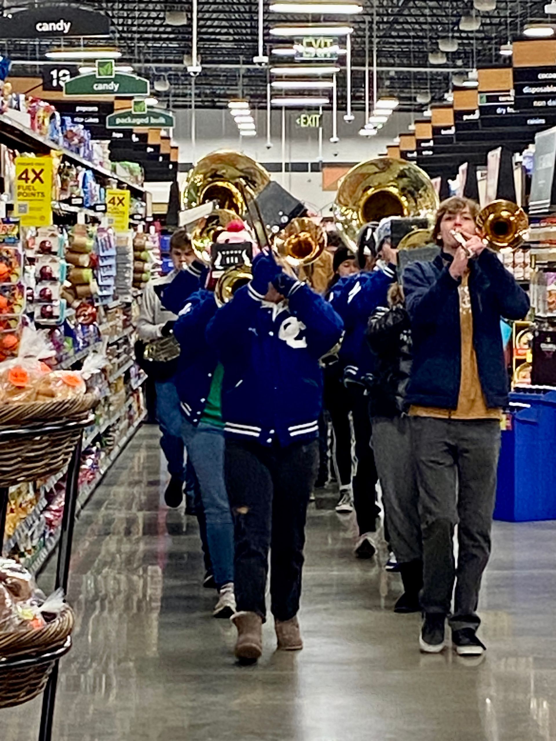 Marching band playing brass instruments in a grocery store aisle