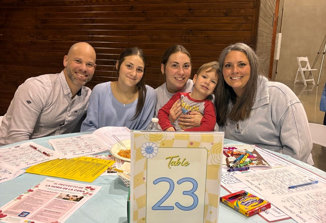 Family posing at a birthday table with a “23” sign and gifts, smiling indoors