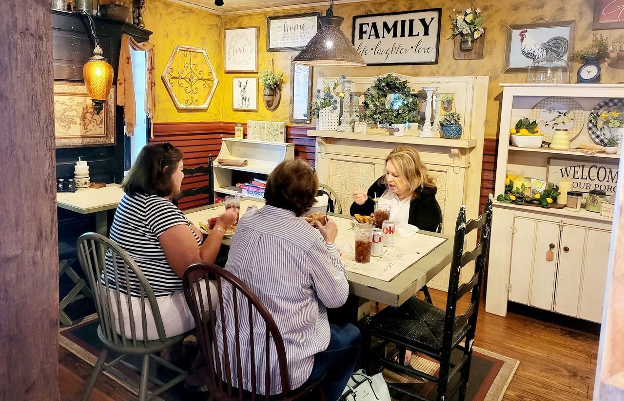 Three women seated at a cozy café table, chatting in a yellow rustic dining room