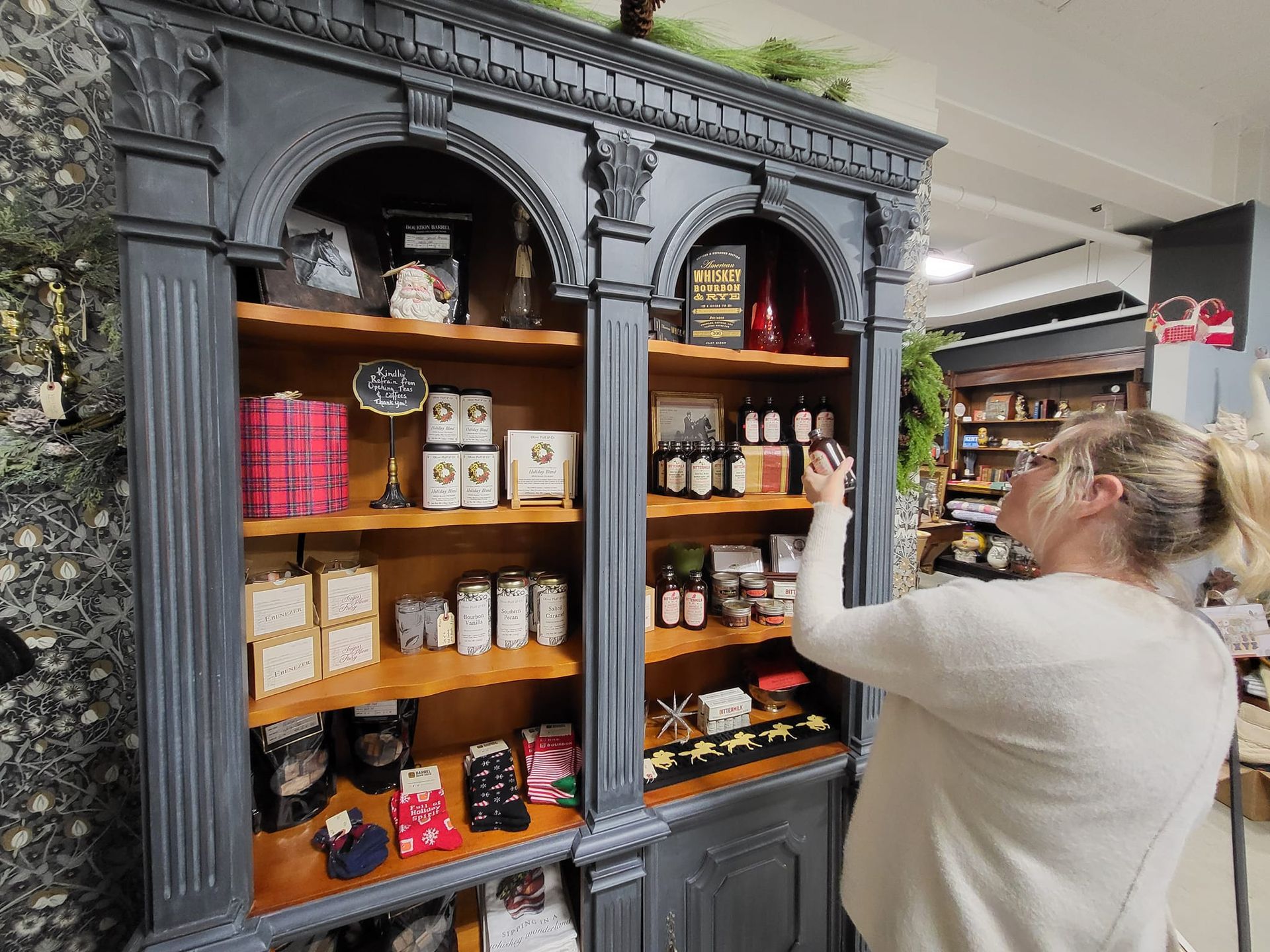 Person browsing a decorative black shelving unit stocked with jars and packaged goods in a store