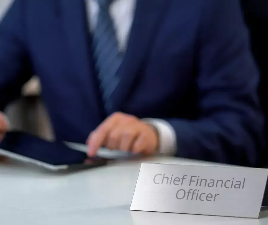 A man in a suit is using a tablet next to a sign that says chief financial officer