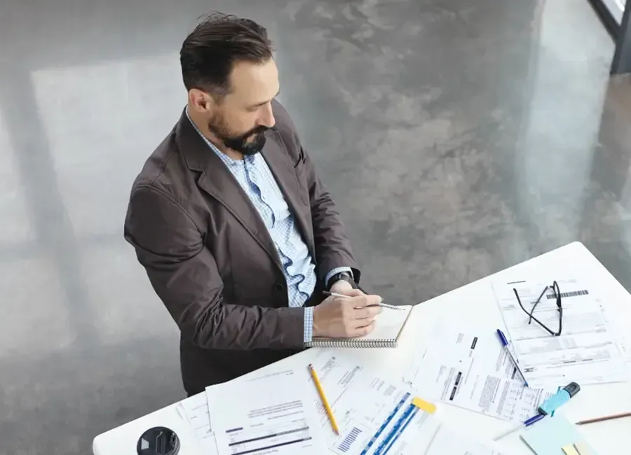 A man sitting at a table with papers and pens.