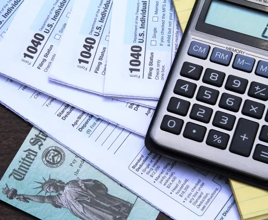 Group of four 1040 IRS Tax Return Forms, a US Cheques and a calculator