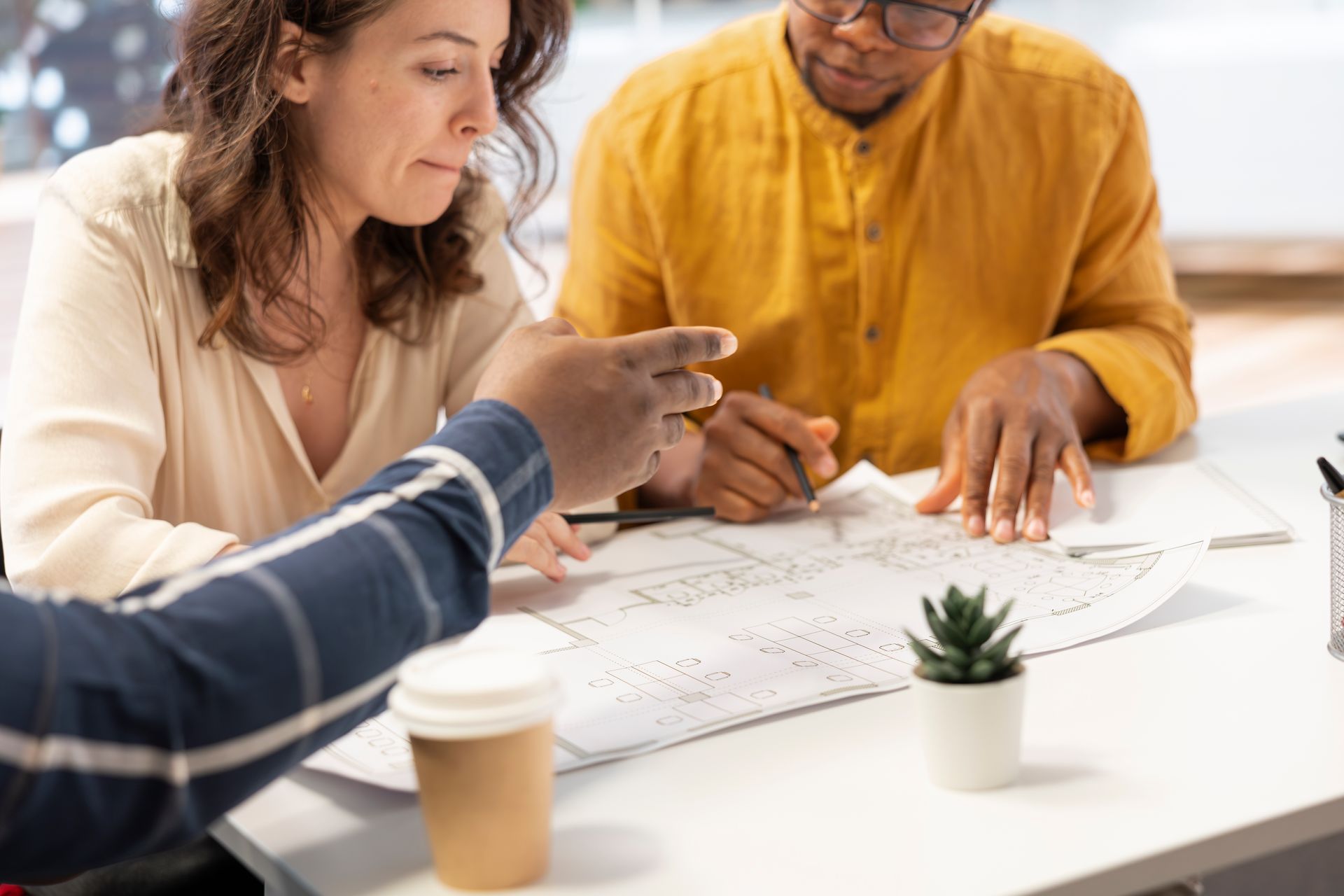 A group of people are sitting at a table looking at a blueprint.