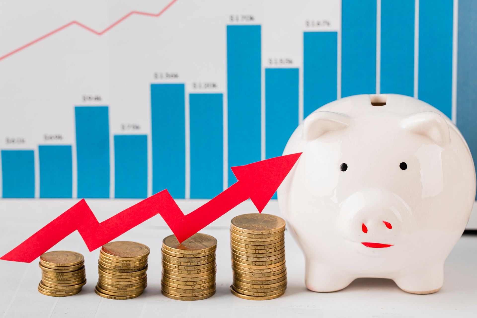 A piggy bank sitting next to stacks of coins with an arrow pointing up.