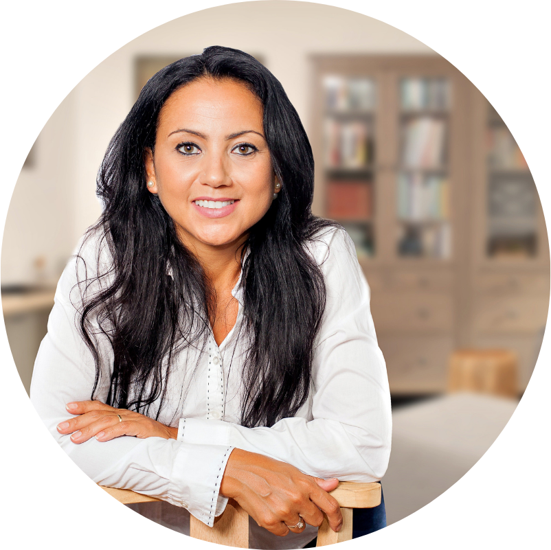 Woman with long dark hair smiles, leaning on chair, office background.