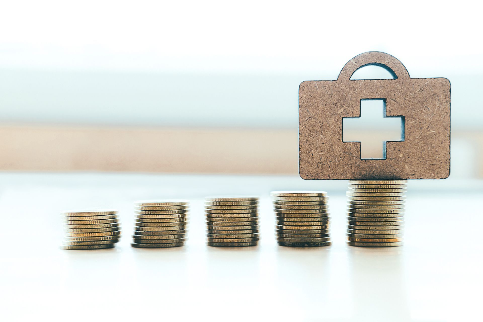 A wooden briefcase with a cross on it is sitting on top of a pile of coins.