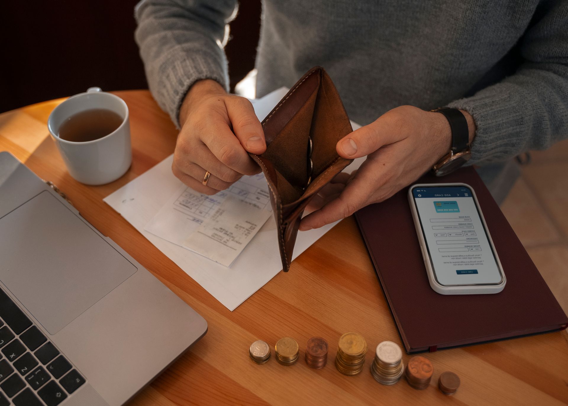 A person is sitting at a table holding an empty wallet.