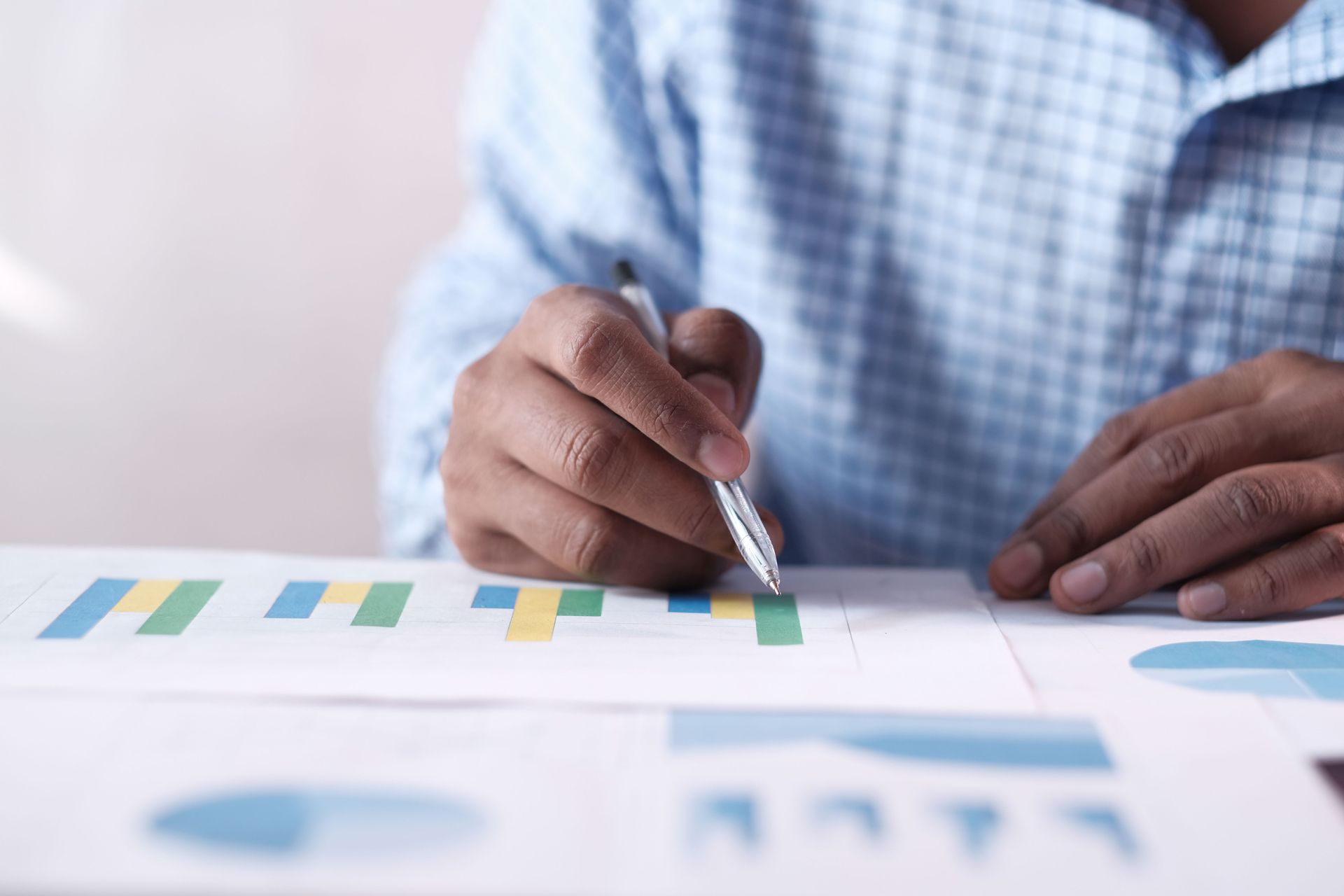 Person pointing to printed charts with a pen during a business meeting