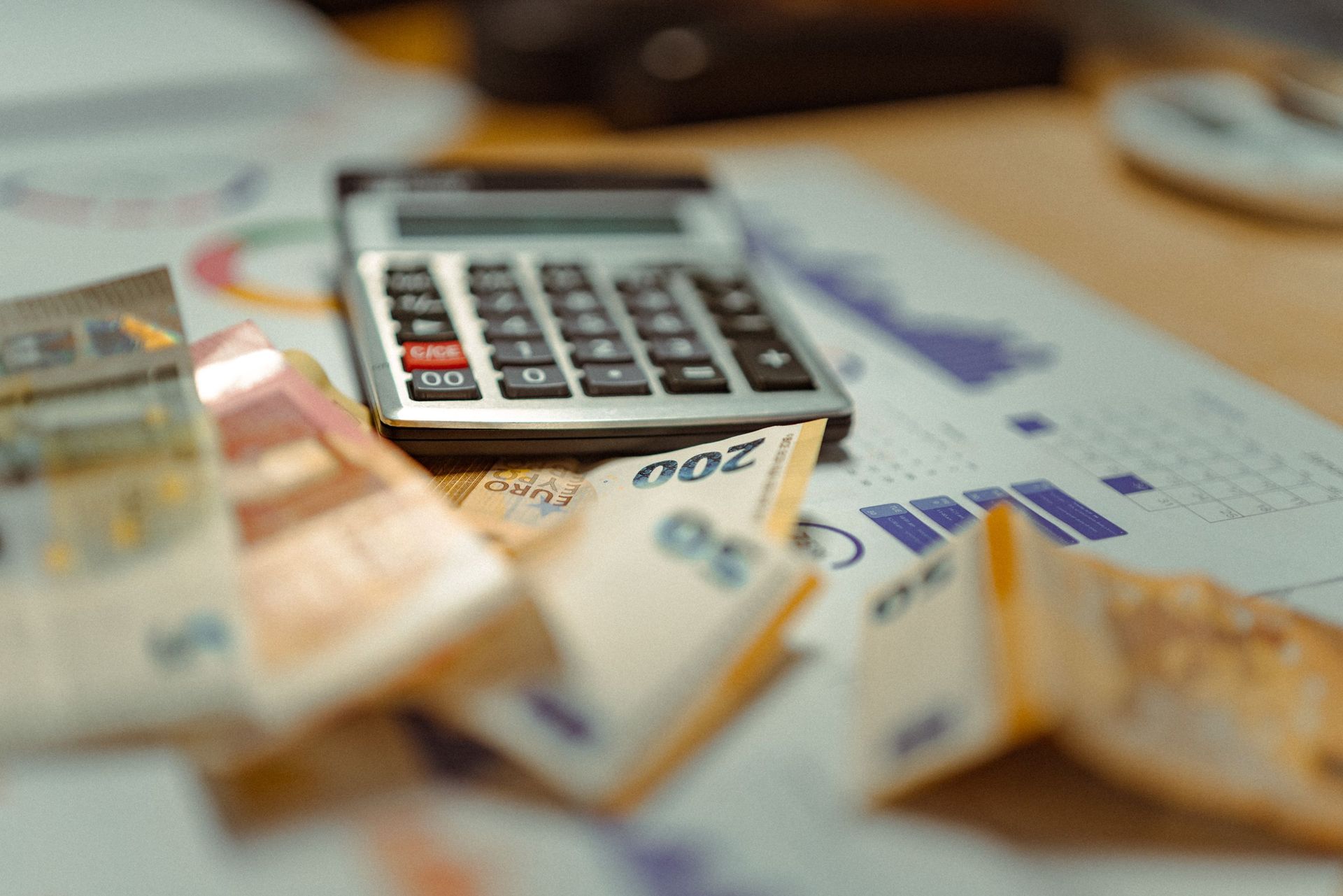 Calculator on euro banknotes with scattered coins on a desk