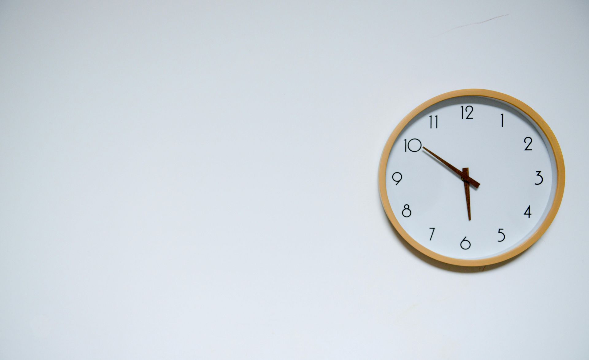 Clock on a white wall, showing the time as 5:50.