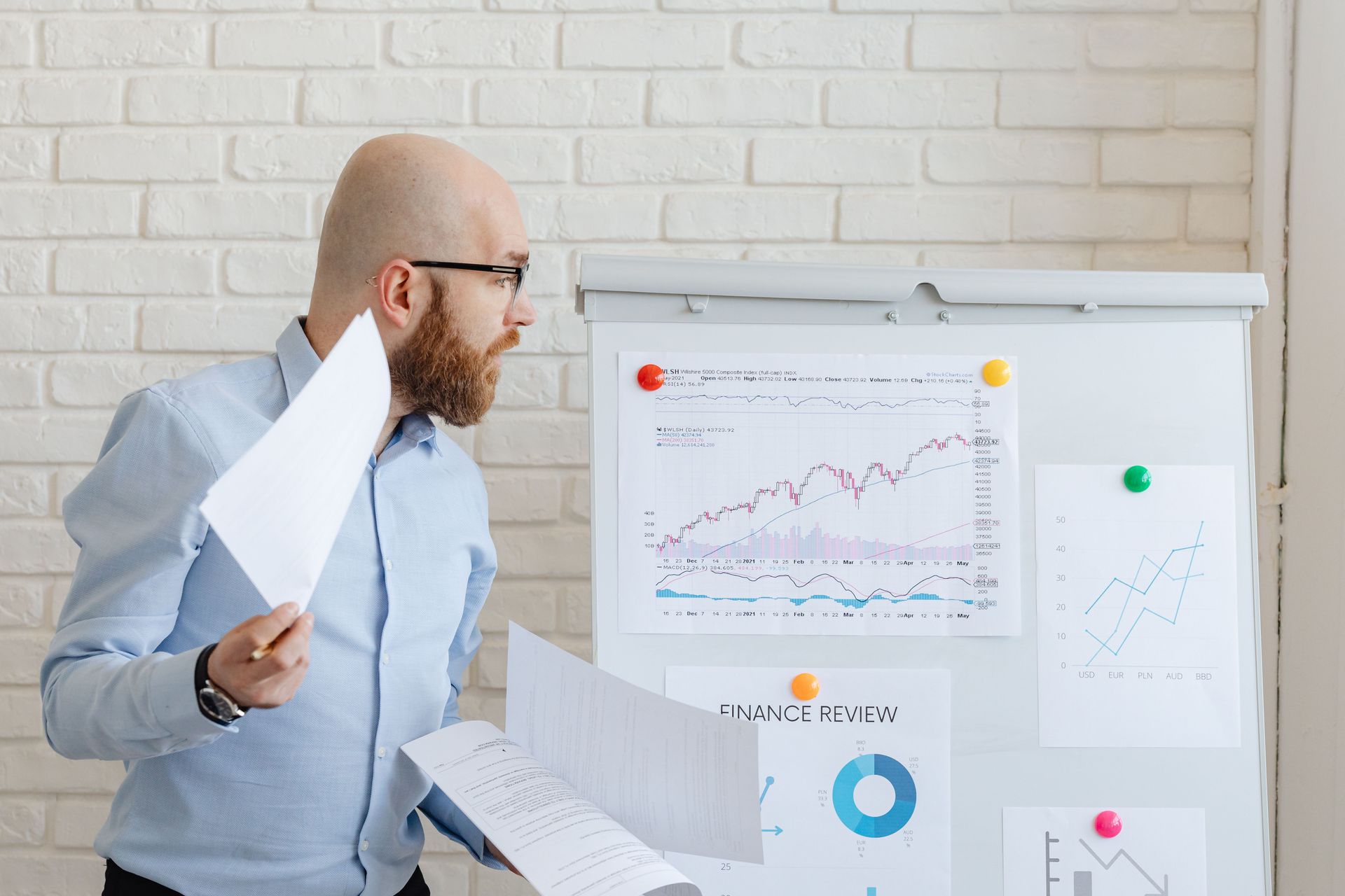 Man presenting charts on a board in a bright office