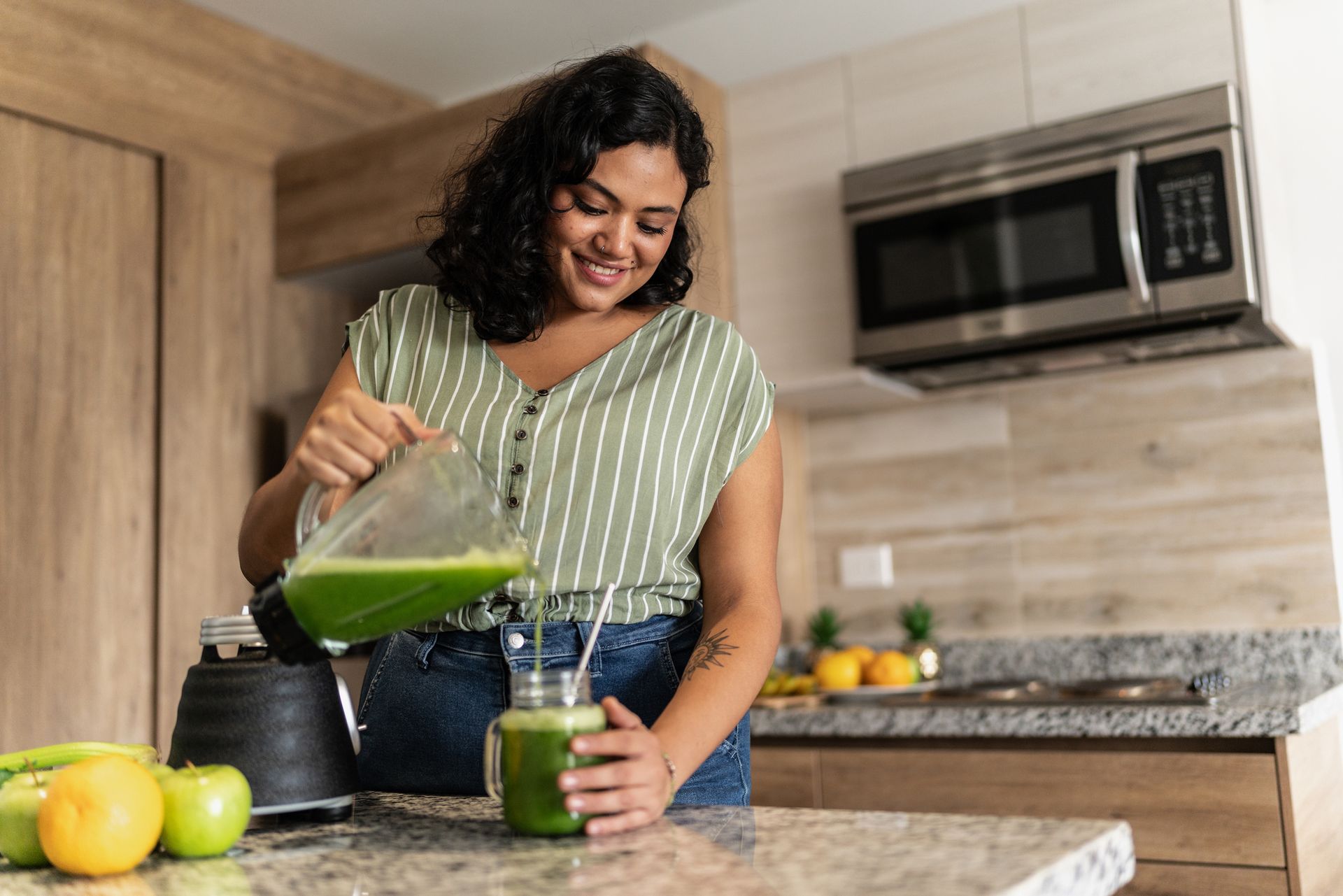 A woman is sitting at a table eating a bowl of fruit.