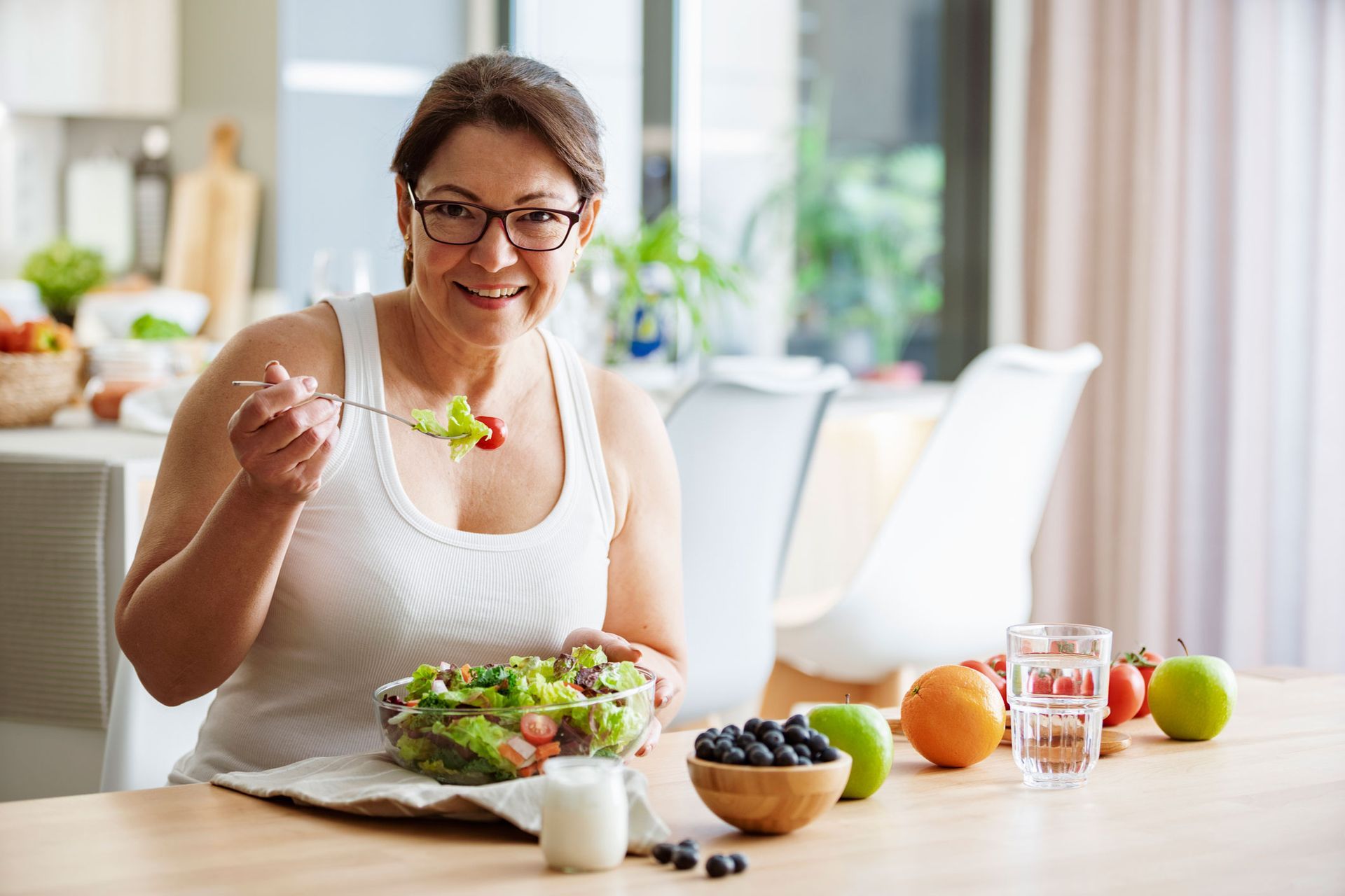A woman is sitting at a table eating a salad.