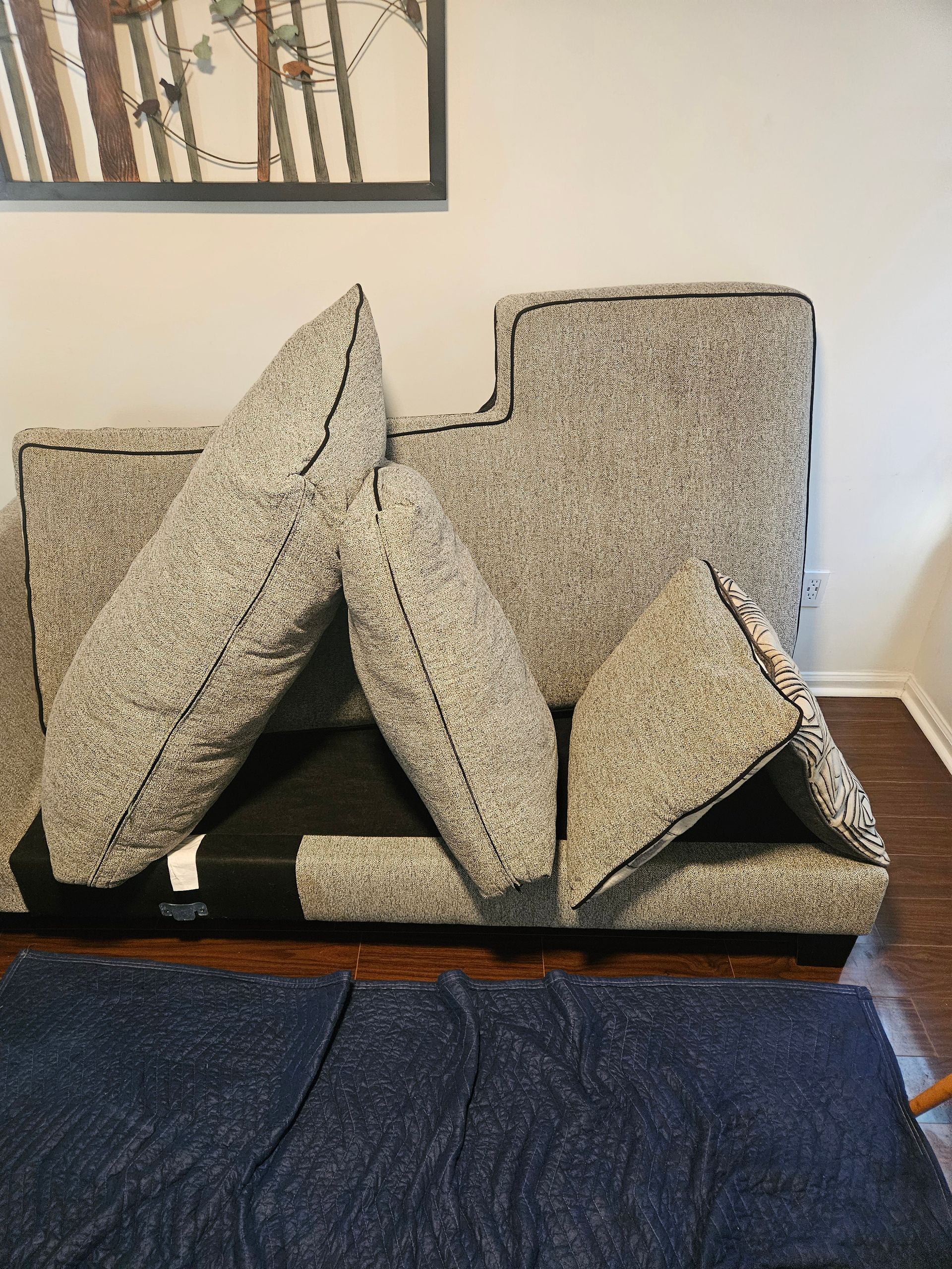 Person cleaning a gray sofa with a handheld vacuum cleaner.