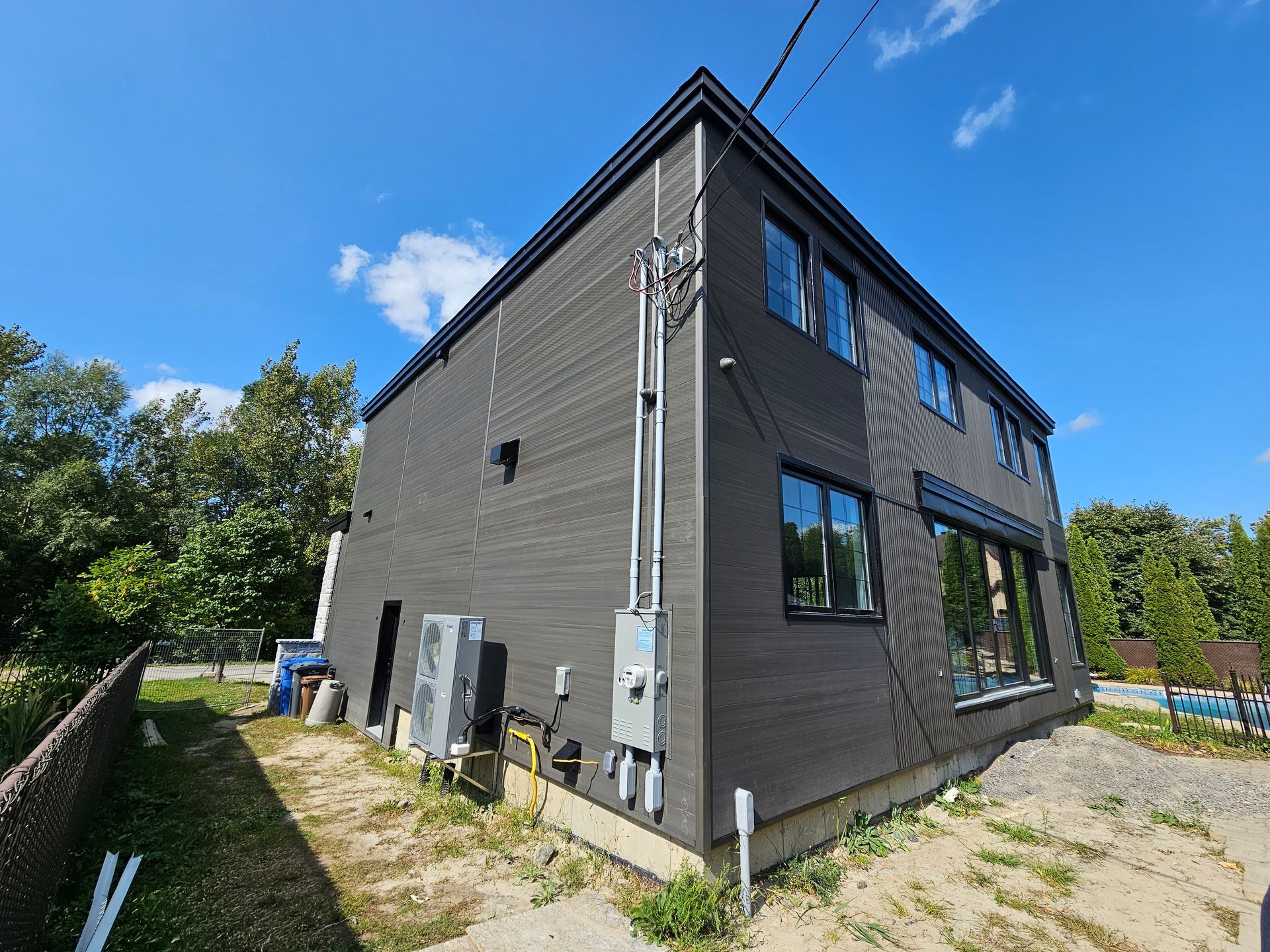 Une grande maison avec beaucoup de fenêtres est située au sommet d'une colline de terre.