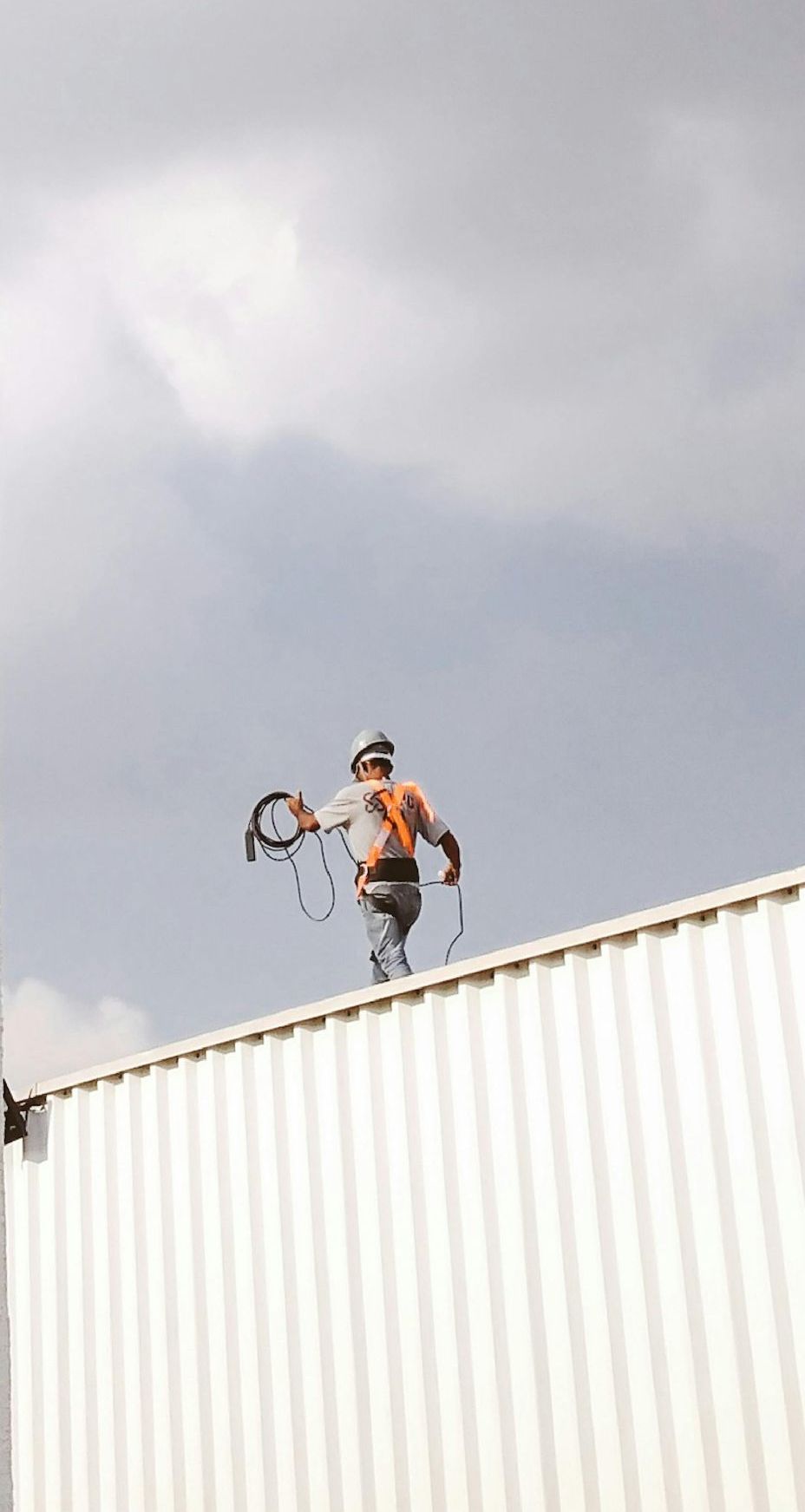 Un homme se tient debout sur le toit d'un bâtiment et tient une corde.
