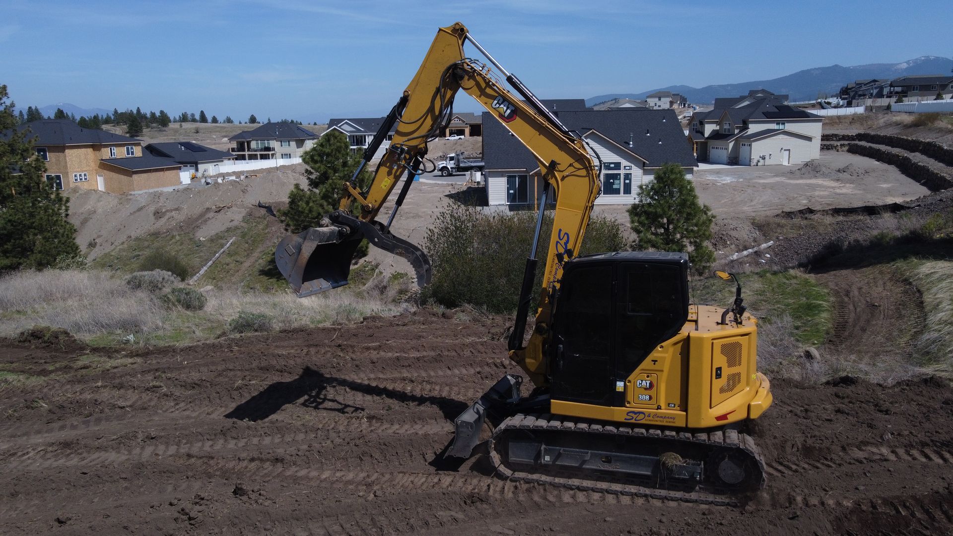 A yellow excavator is moving dirt in a field