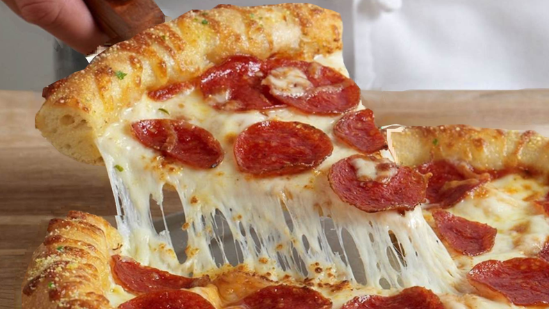 Pepperoni pizza slice being lifted, with melted cheese stretching from the pie